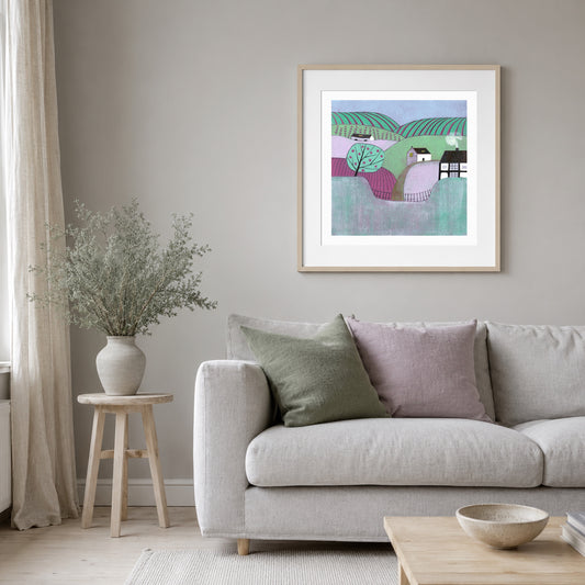 Apple Orchard landscape linocut print framed above a grey sofa with sage and lilac cushions.