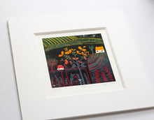 Load image into Gallery viewer, A vibrant linocut print titled "Autumn Glow" is framed and displayed alongside a lino cutting tool. The artwork depicts a stylised landscape with an autumn tree, a white house, and plants. The edition number and artist's signature are visible below the print.