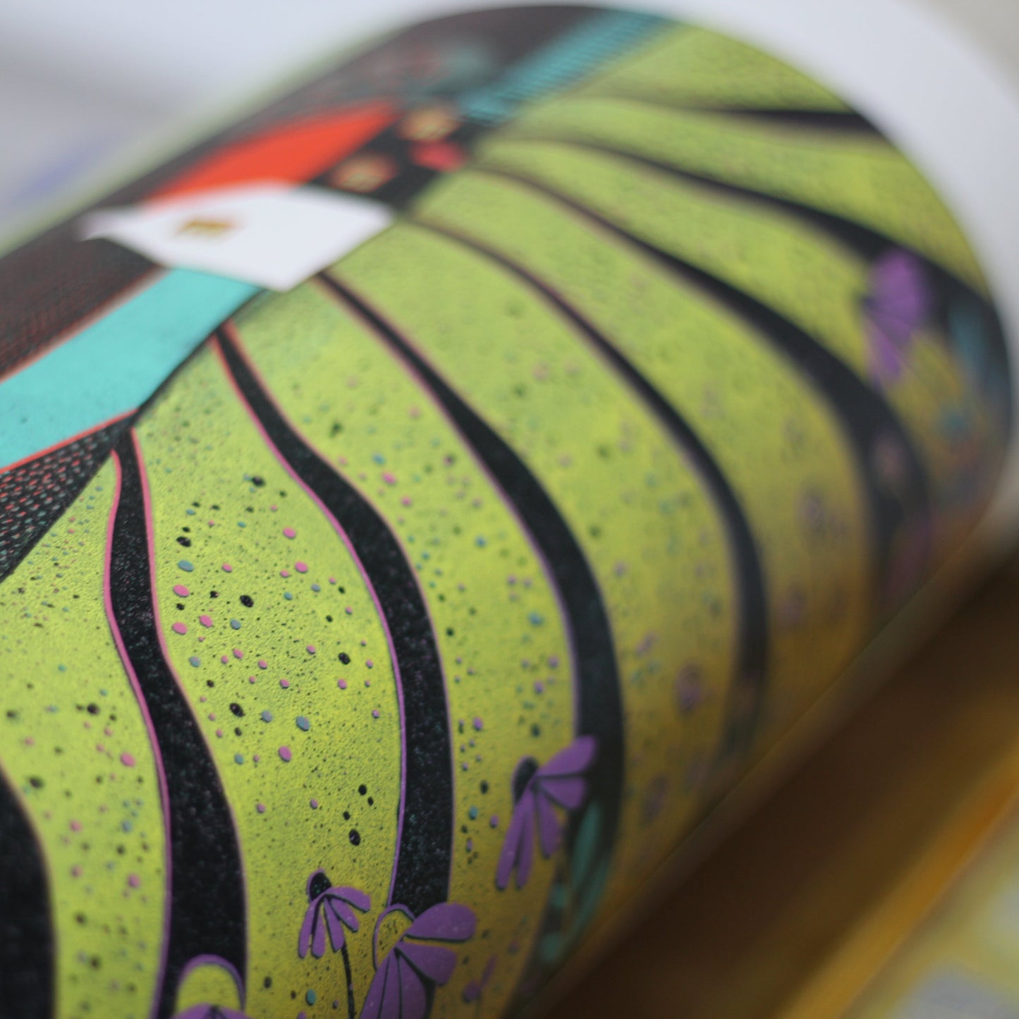 Close-up of the hand-printed cottage, furrowed fields and purple flowers in the linocut.