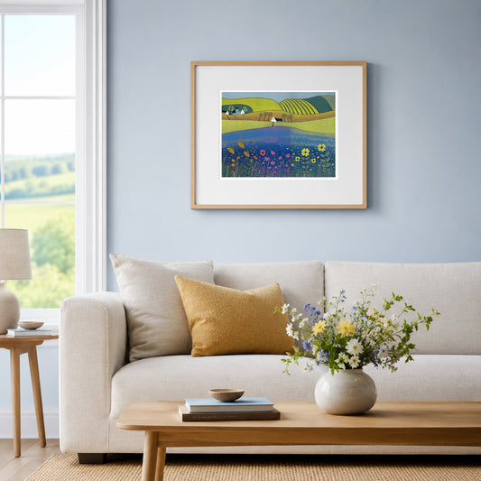 Sea of Tranquility print framed in pale oak on a soft blue wall above a linen sofa with a mustard cushion and wildflowers.