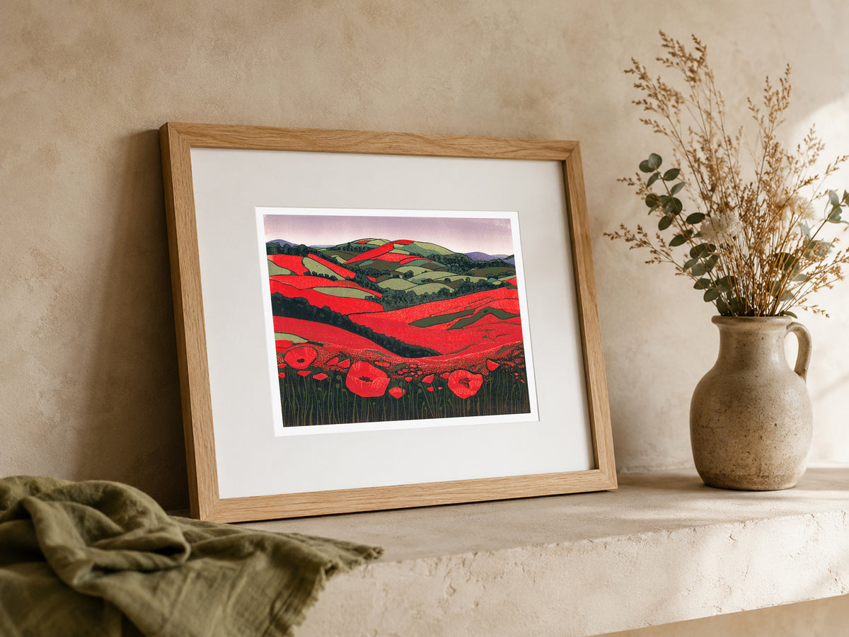 Poppies Unveiled colourful landscape linocut print framed and leaning on a mantel