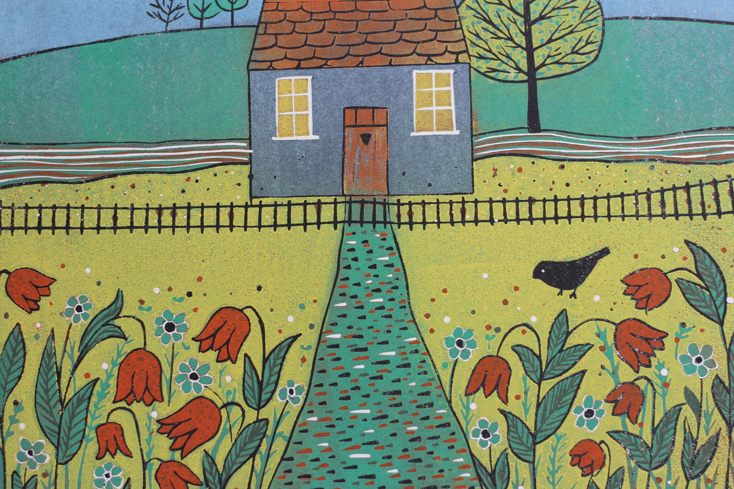 Close-up of Beyond the Garden reduction linocut showing the cottage, birds, flowers and hand-printed carved texture.