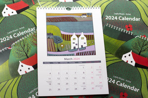 Open view of the 2024 Linocut Wall Calendar, showcasing the March 2024 page featuring a captivating linocut print of a rural landscape with charming houses, a creation by Laylart Studio.