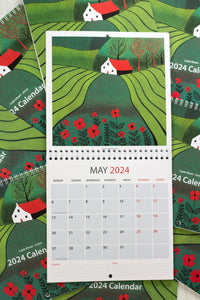 May 2024 calendar in 30 x 60 cm size, showcasing an open view of the entire calendar, featuring a picturesque linocut print of a rural landscape with a distant house, expansive lands, and vibrant red flowers in the foreground