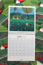 Load image into Gallery viewer, June 2024 Wall Art Calendar fully opened, featuring a colorful linocut print landscape. The image displays the date section and includes space for priorities and notes at the bottom.