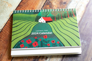 Front cover of the 2024 Desk Calendar, adorned with a captivating linocut print in bold and vibrant colors, crafted by Laylart Studio.