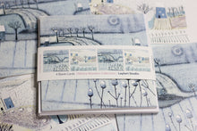 Load image into Gallery viewer, Close-up of the Wintry Wonders Collection Christmas cards pack, displaying four cards with two distinct snowy winter scenes in soft blues, grays, and whites. Each design is featured twice, highlighting the serene snowing effect.