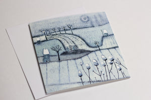 Christmas card from the Wintry Wonders Collection, illustrating a peaceful snow-covered landscape in muted blues and grays with a snowing effect, rendered in a detailed linocut print.