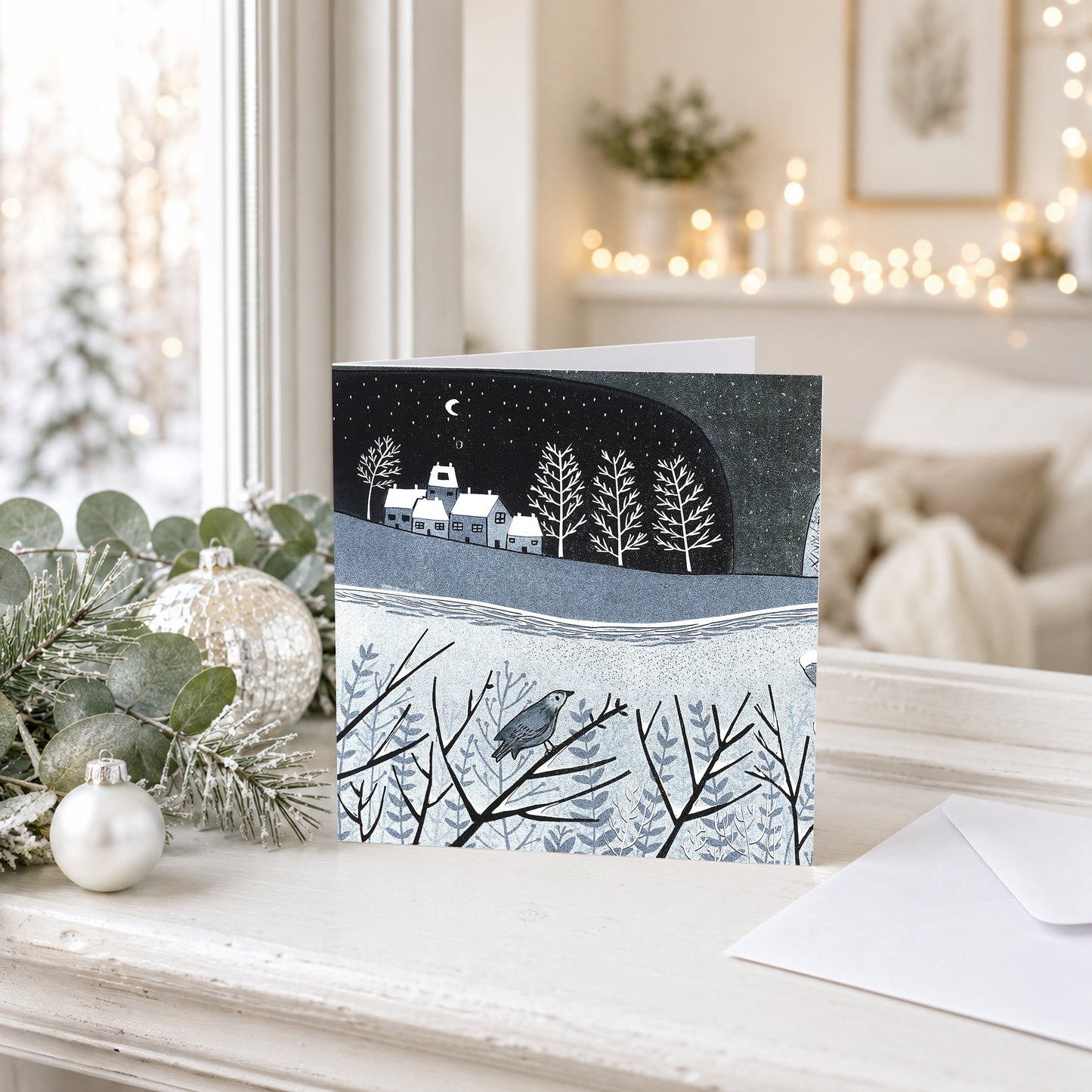 Wintry Nights Christmas card with a snowy blue landscape displayed in a softly lit festive interior.