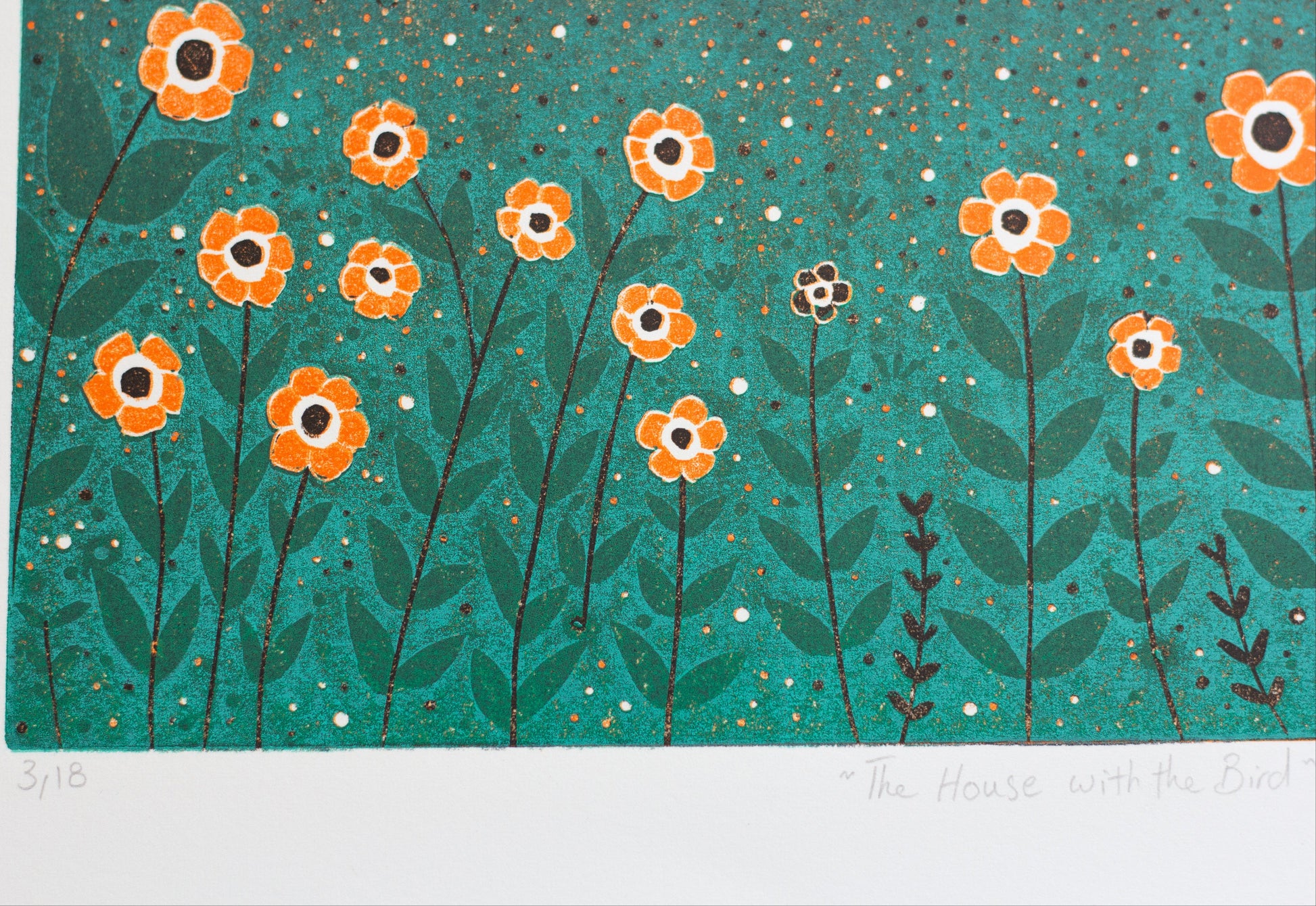 Close-up of The House with the Bird reduction linocut print showing orange flowers, hand-printed texture, edition number and handwritten title.