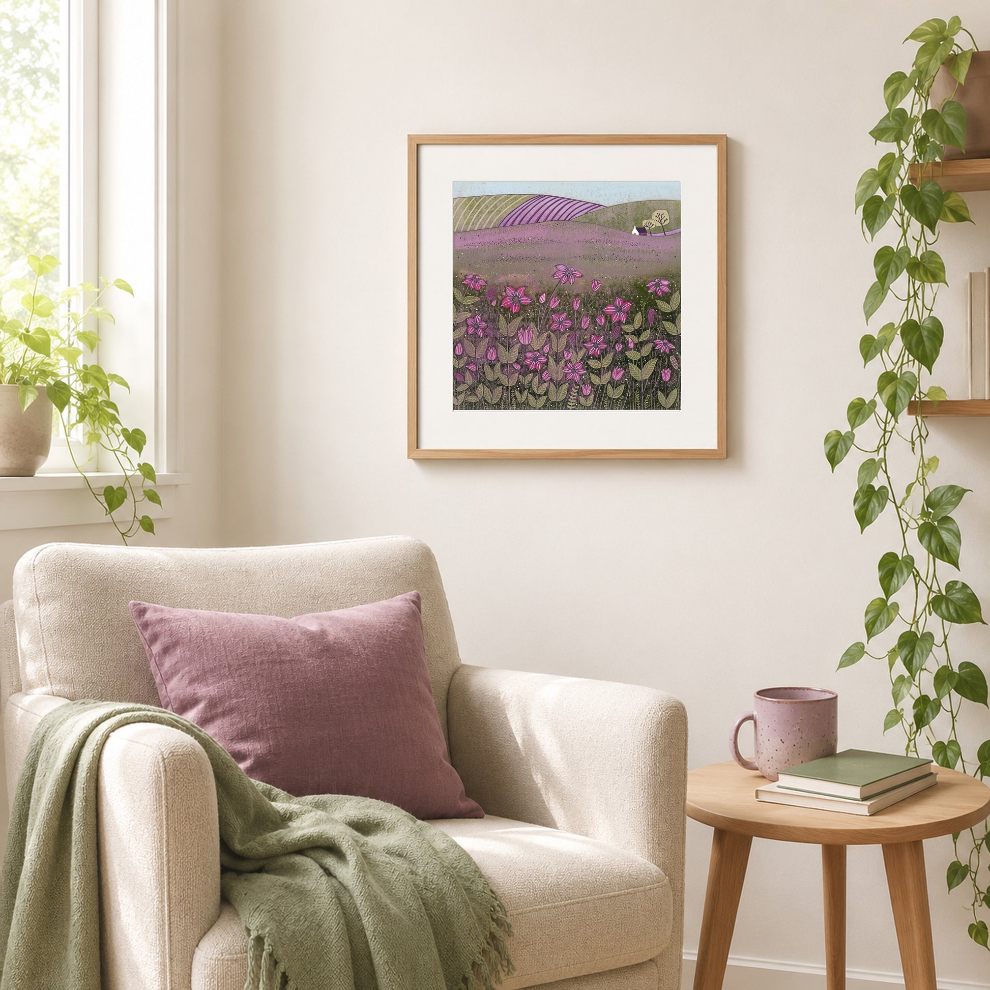 Purple meadow linocut print framed in oak above a cream armchair with a mauve cushion and sage throw.