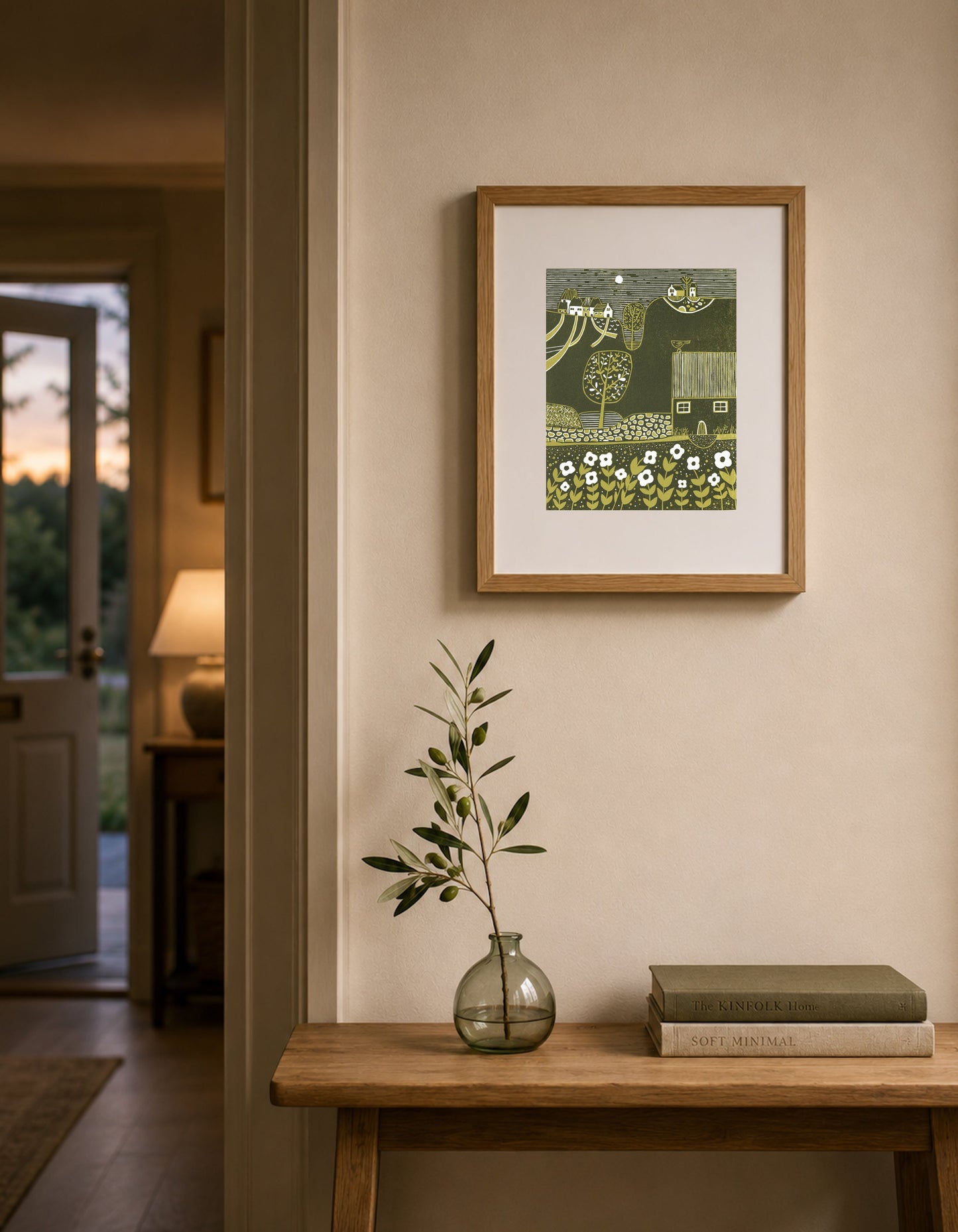 Framed Serene Hillside linocut print displayed above a wooden console table in a warm neutral interior.