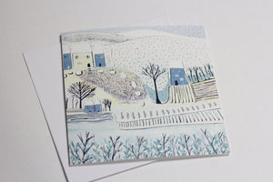 Christmas card from the Wintry Wonders Collection, featuring a subtle snowy scene in shades of blue, gray, and white. The linocut print portrays a gentle snowfall, ideal for holiday cheer.