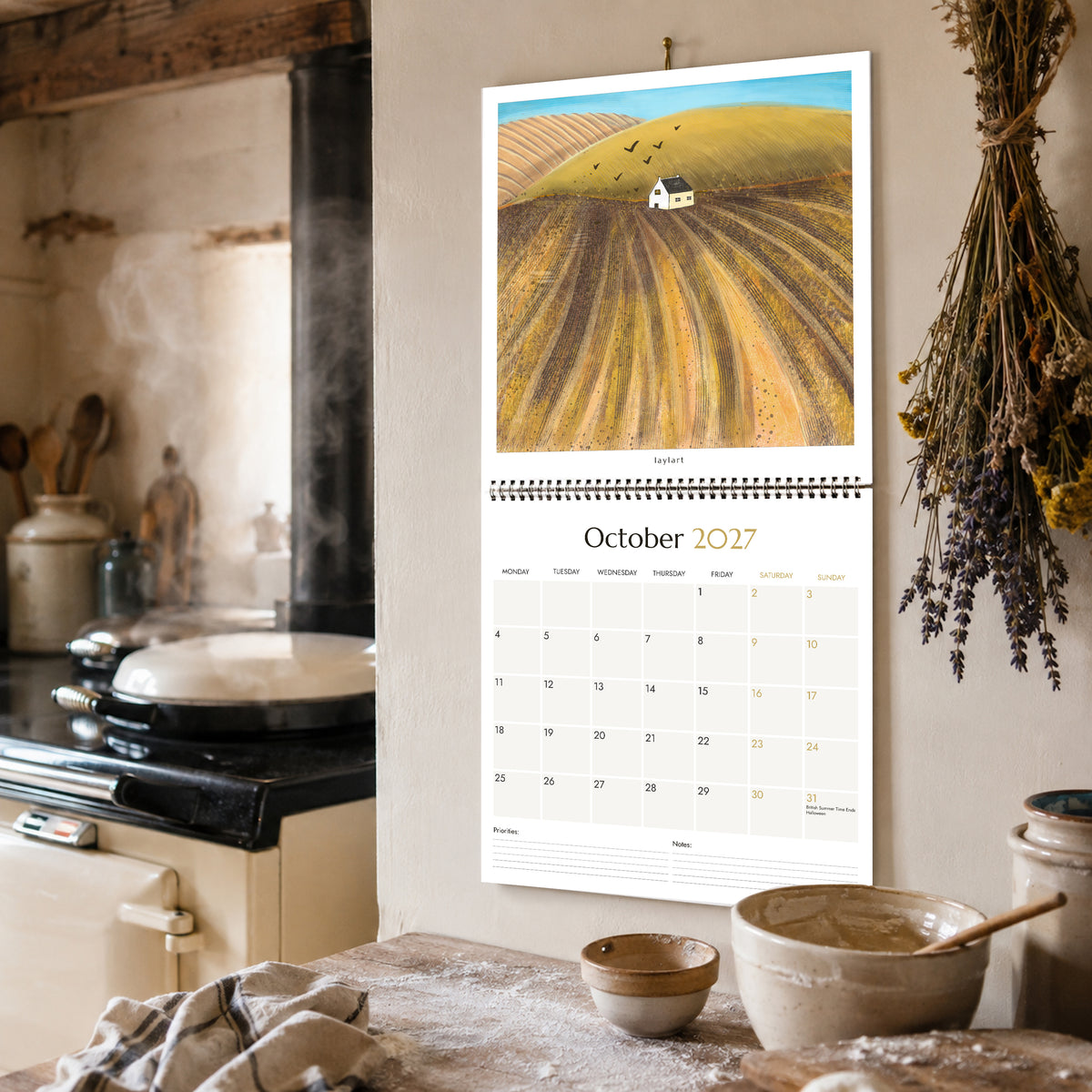 2027 square wall calendar open to October with autumn landscape painting in a country kitchen