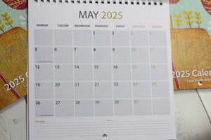 May 2025 wall calendar featuring a vibrant linocut artwork by Layla Khani.