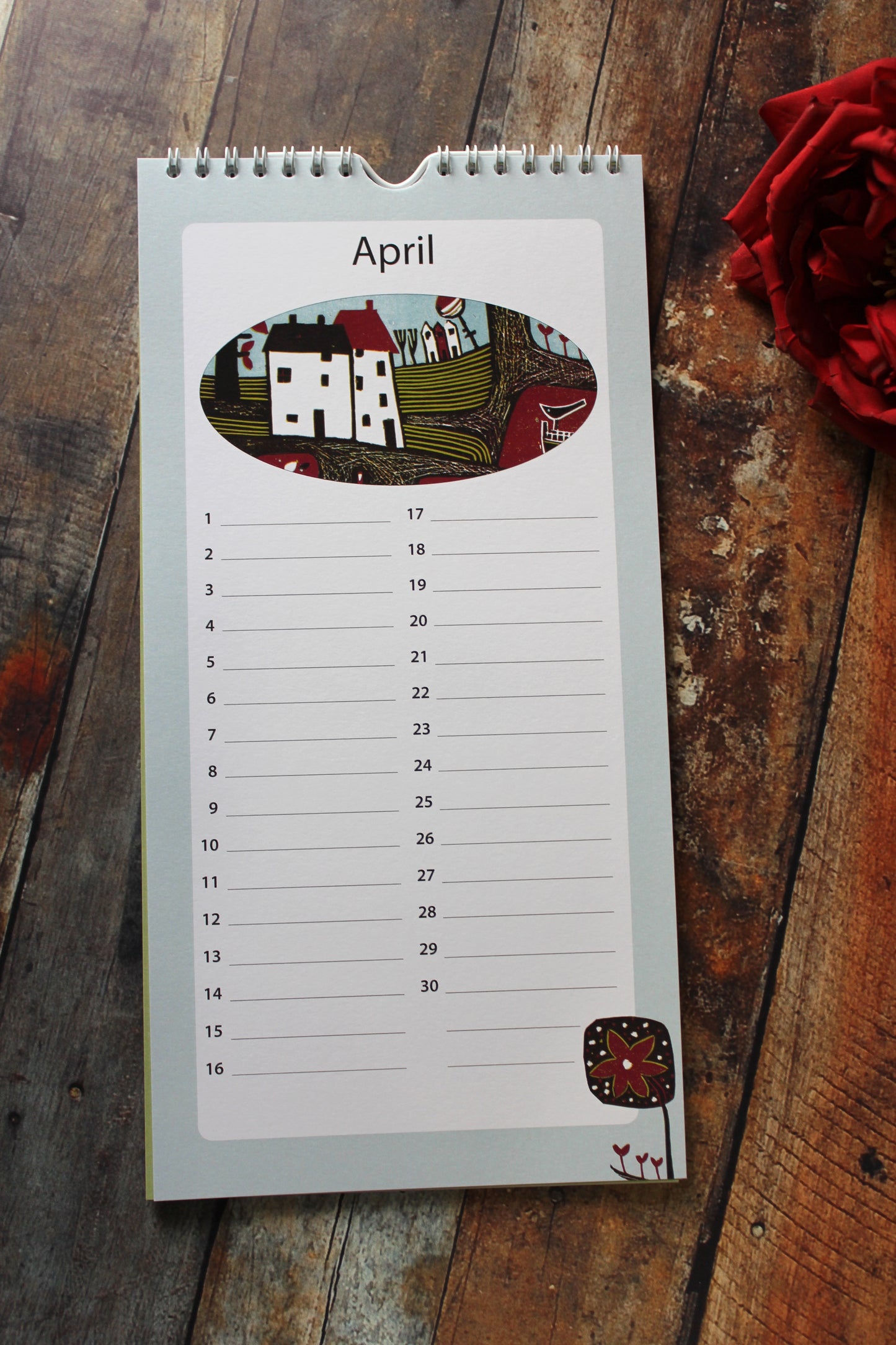 Laylart linocut birthday calendar open to April with linocut village scene