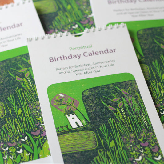 Laylart linocut birthday calendar cover with green landscape print and white cottage